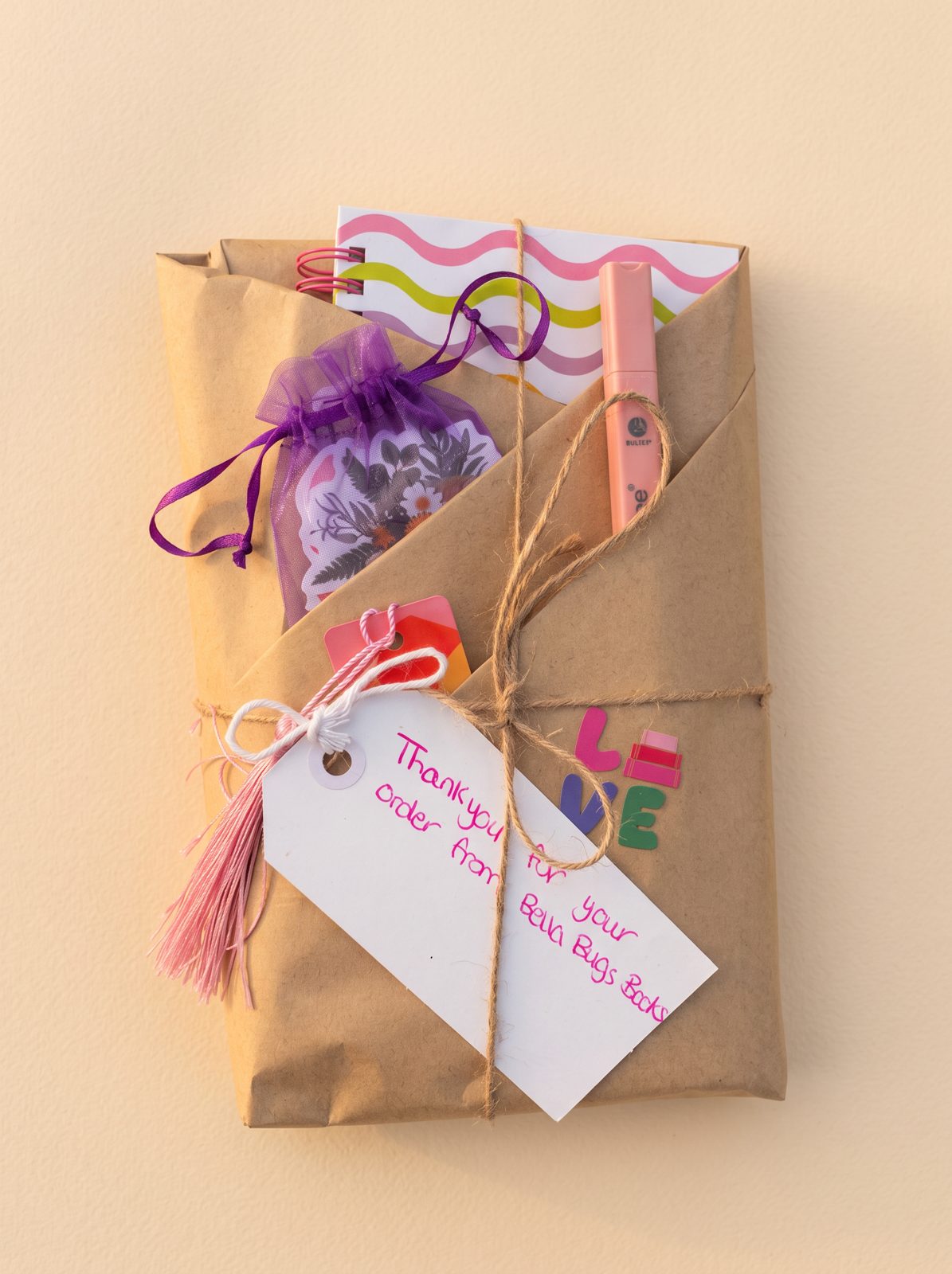 A brown paper parcel tied with twine, a pink highlighter and stickers
