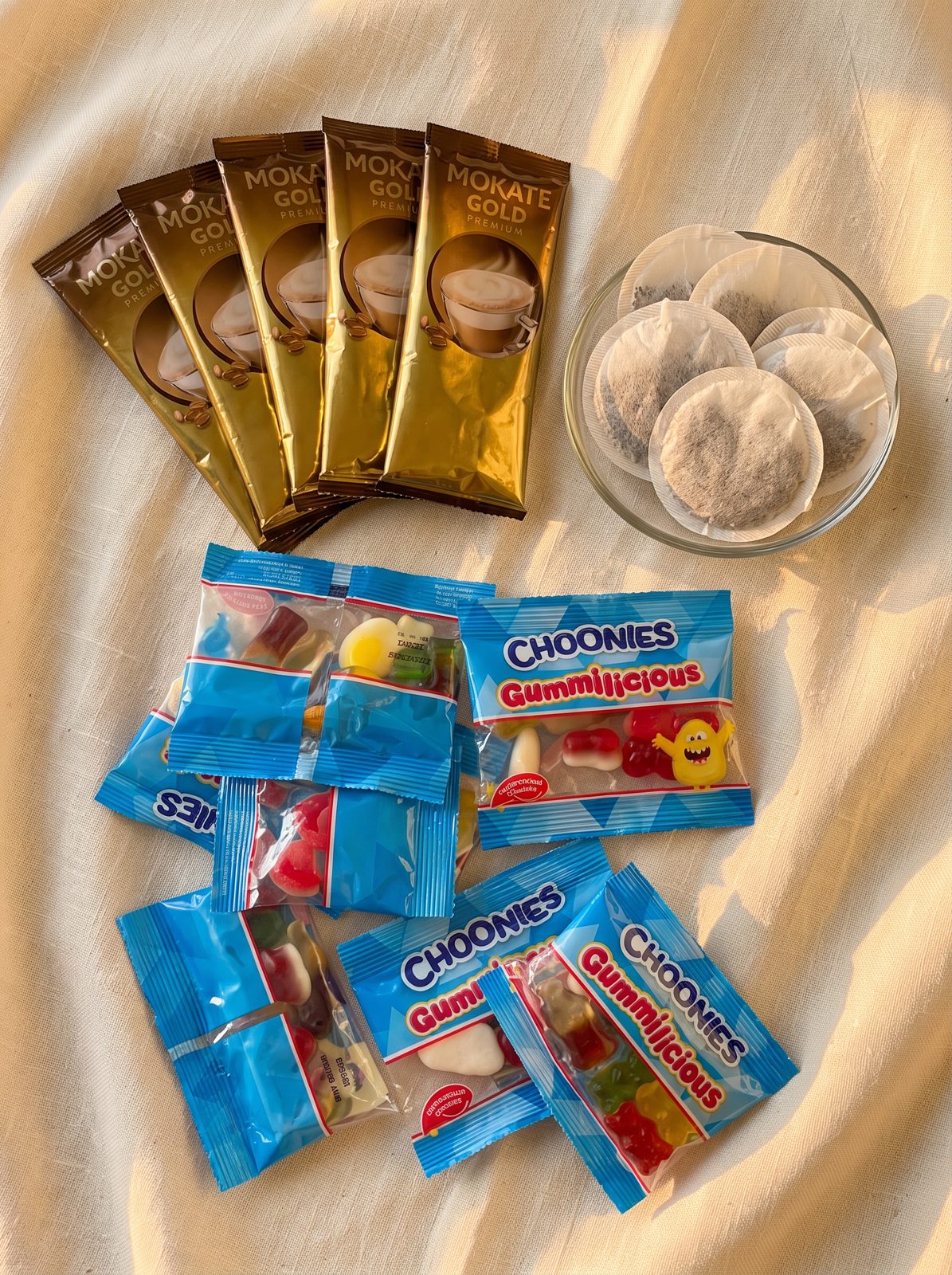 Hot chocolate sachets and sweet treats laid out on a cream surface